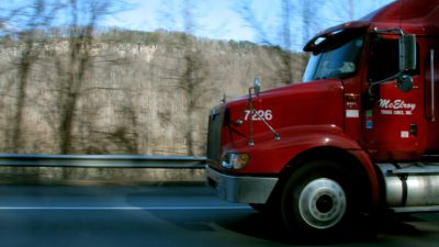 En stor röd lastbil kommer inkörande från höger.