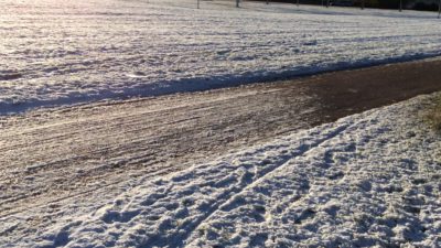 Bilden föreställer en cykelbana med snö på båda sidor. I övre, vänstra kanten skymtar solen.