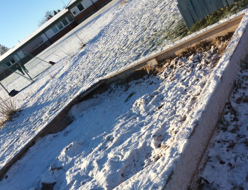 En sandlåda täckt i snö. Solen lyser klart.