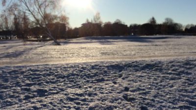 Solen står lågt på himlen. Den nuddar nästan trädtopparna och hustaken, borta vid horisonten. Framför dem ligger snön på marken.