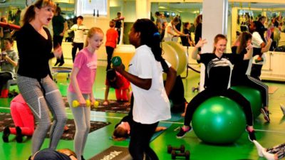 Tre barn och en vuxen tränar styrka på ett gym.