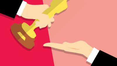 En tecknad bild på två armar med svarta kostymer. Den ena handen ger en oscarsstatyett till den andra handen. Statyetten är formad som en gubbe och är gjord av guld.