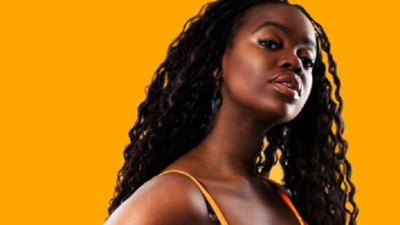 Renaida står framför en gul bakgrund. Hon har ett gult linne på sig. Hon lutar huvudet åt vänster och tittar snett in i kameran. Hon har långt svart vågigt hår.