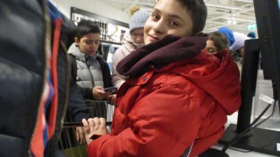 Ett barn i röd jacka tittar in i kameran.