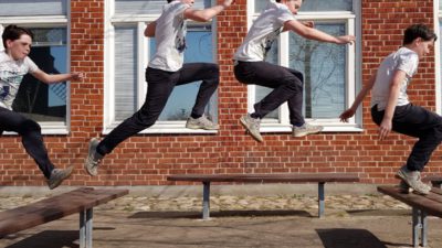 En skolelev hoppar mellan två bänkar. Vi ser honom på fyra olika ställen i luften.