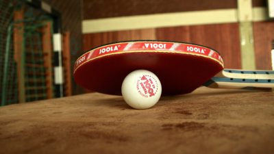 Bild på ett pingisrack som ligger lutad mot en pingisboll.