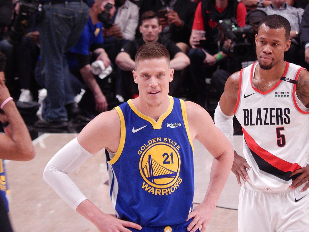 Jonas Jerebko står med händerna på höfterna och väntar på att bollen ska sättas igång i matchen mot Portland. Precis bakom honom står en av motståndarna och i bakgrunden syns publiken på läktarna.
