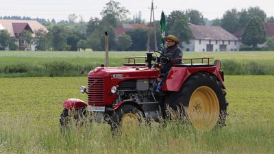 En bonde åker en röd traktor.