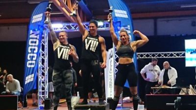 Martina står på medaljpodiet och lyfter upp en pokal i luften.