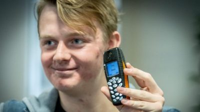 Simon håller upp en gammal mobiltelefon