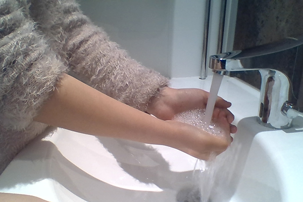 En elev som tvättar händerna under rinnande vatten.